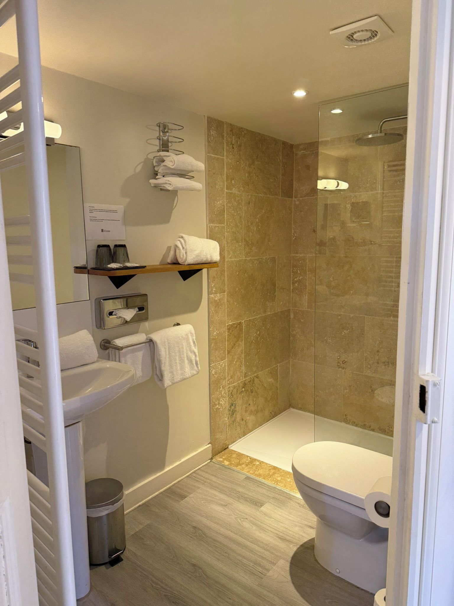 A modern bathroom with a glass-enclosed shower, a toilet, and a sink.