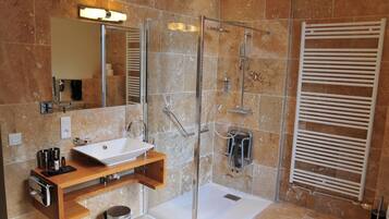 A modern bathroom with a glass-enclosed shower, a white sink, and a wooden vanity.