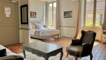 Habitación de hotel con cama, una silla, una mesa y ventana con cortinas.
