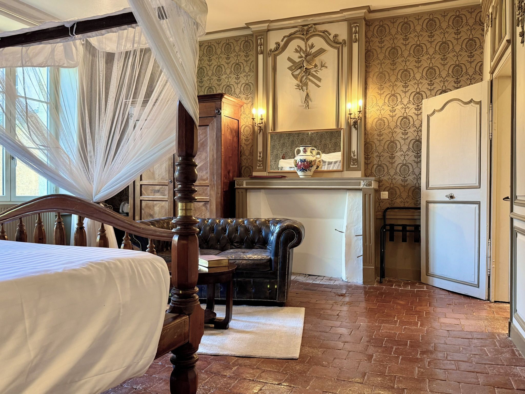 Un dormitorio con cama con dosel, un sofá de cuero y un comedor con mesa y sillas.