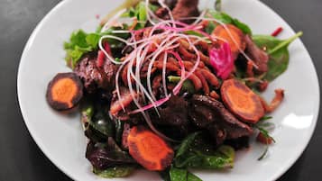 A plate of food with sliced carrots, leafy greens, and possibly meat, garnished with thinly sliced red onions.