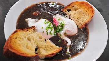 A plate of food with a poached egg, black sauce, and toasted bread.