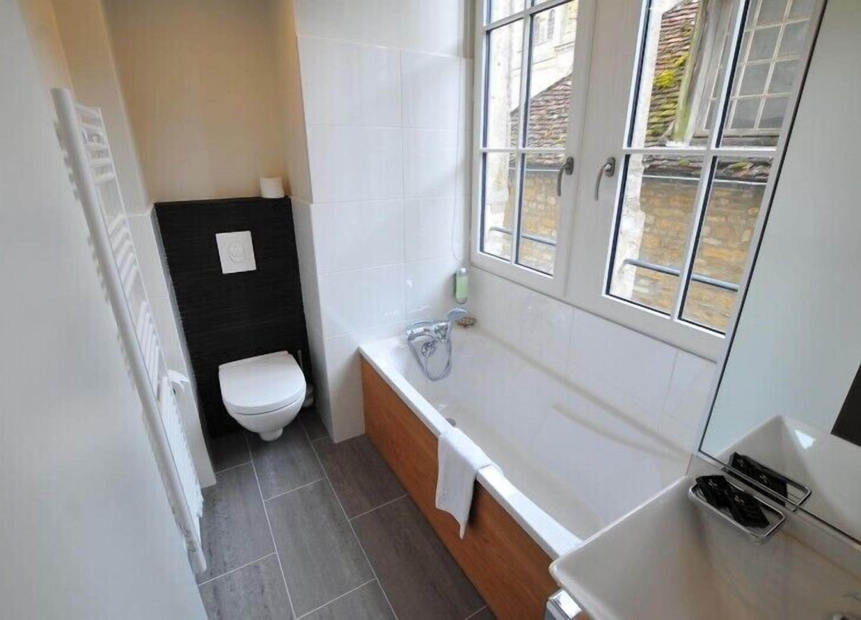 A compact bathroom with a toilet, bathtub, and a window.