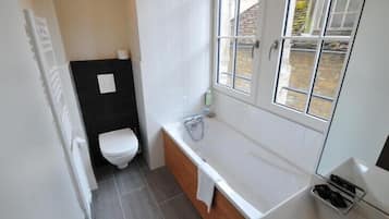 A compact bathroom with a toilet, bathtub, and a window.