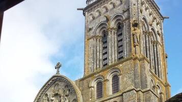 A historic stone building with a tall tower featuring arched windows and intricate carvings.