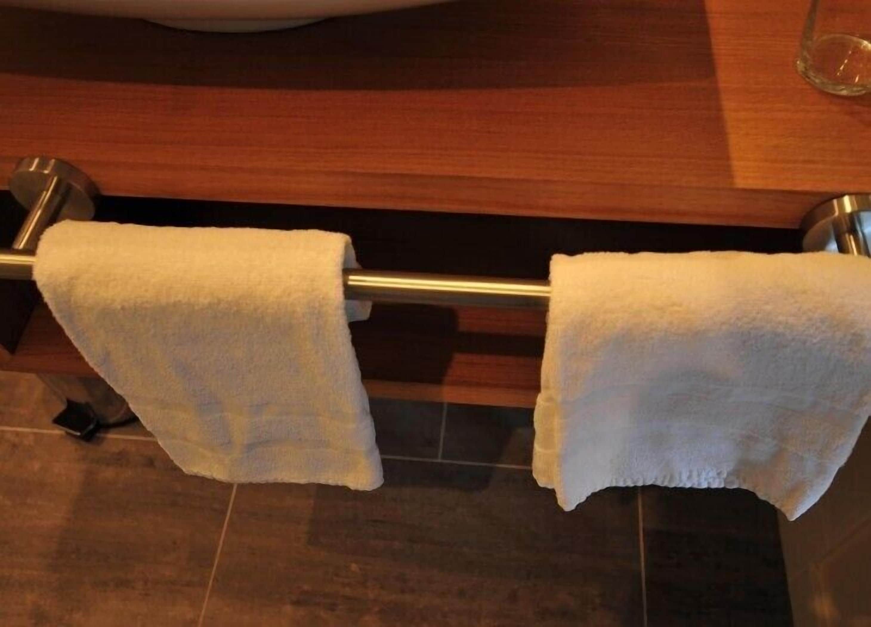Un baño con dos toallas blancas colgadas en un perchero metálico.