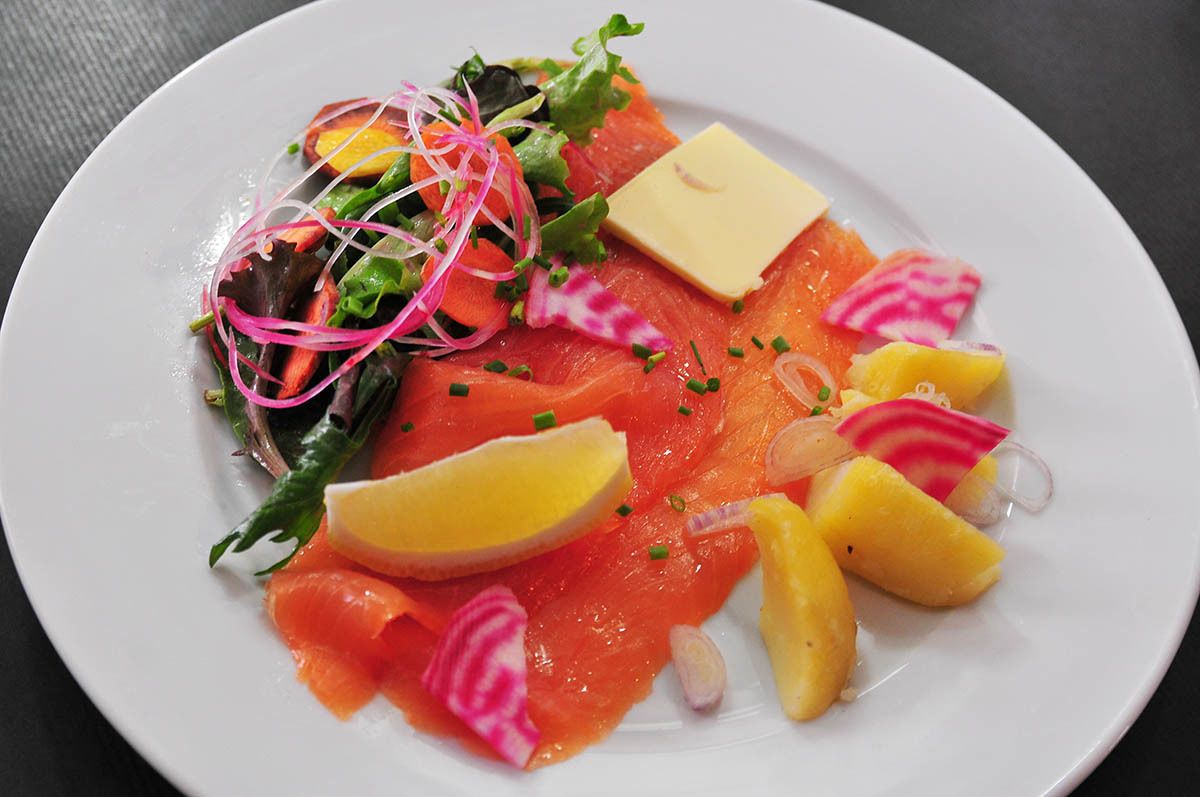 Ein Teller mit Lachs, Zitronenscheiben und Salat.