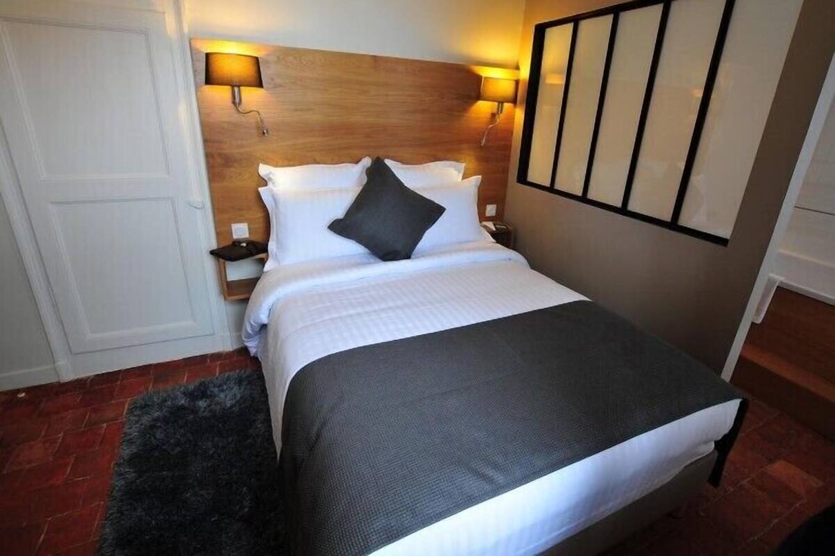 A neatly arranged hotel room with a bed, bedside lamps, and a headboard.