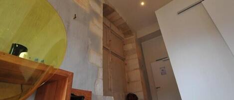 Una habitación con un escritorio de madera, un espejo grande y una escalera que lleva a otro nivel.
