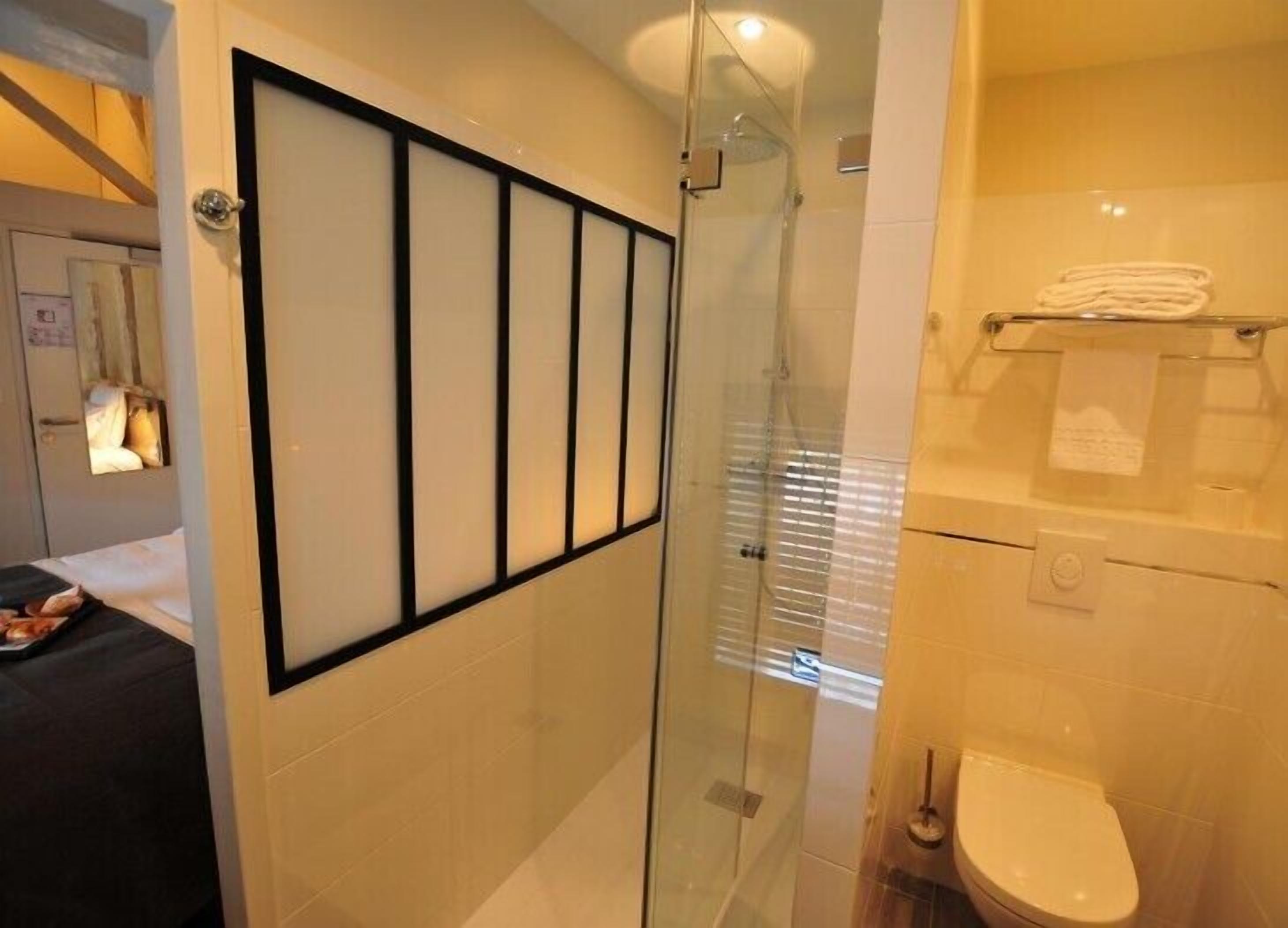 A modern bathroom with a glass shower enclosure, a toilet, and a towel rack.