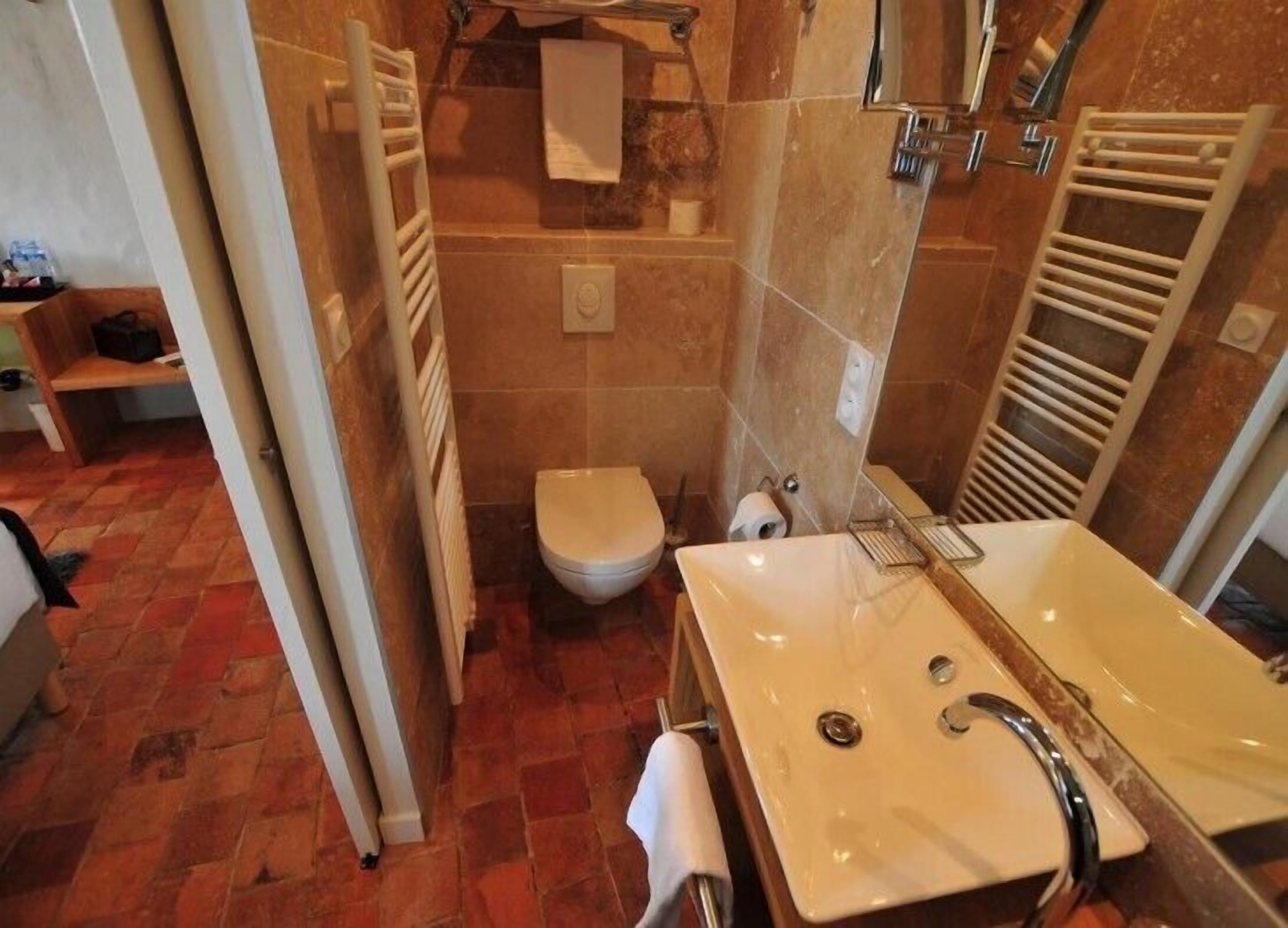 Une salle de bain équipée de toilettes, d’un lavabo et d’un porte-serviettes.