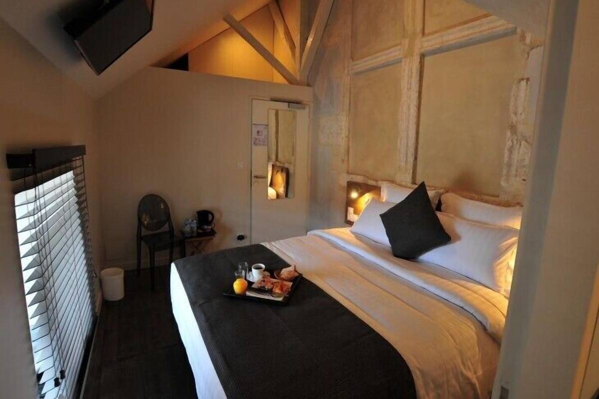 A cozy bedroom with a bed, bedside table, and a small chair.