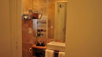 Une salle de bain avec un mur en marbre, un lavabo blanc, un porte-serviettes et un miroir.