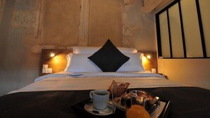 A cozy bed with a black pillow, a tray with breakfast items, and a nightstand with a lamp. - Hôtel & Restaurant SY La Terrasse (Vezelay)