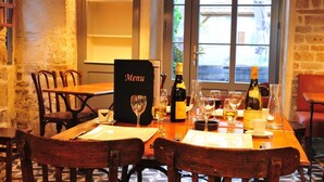 A restaurant table set with wine glasses, a menu stand, and a bottle of wine. - Hôtel & Restaurant SY La Terrasse (Vezelay)