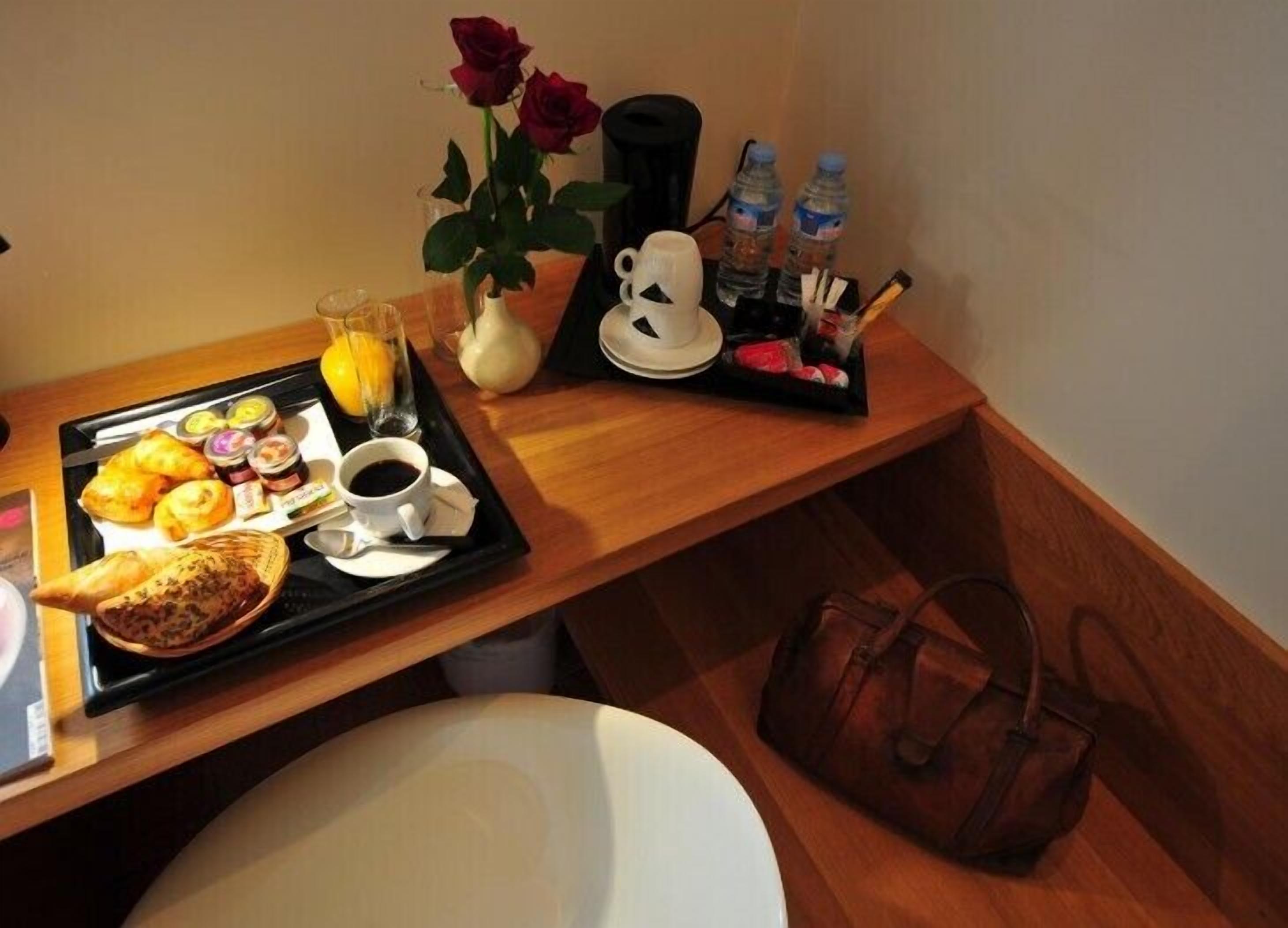 A breakfast tray with croissants, a glass of orange juice, and a cup of coffee on a wooden table.
