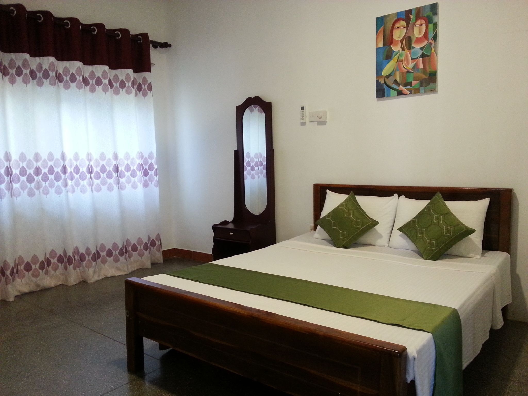 Una habitación de hotel con cama, espejo, un cuadro en la pared y ventana con cortinas.
