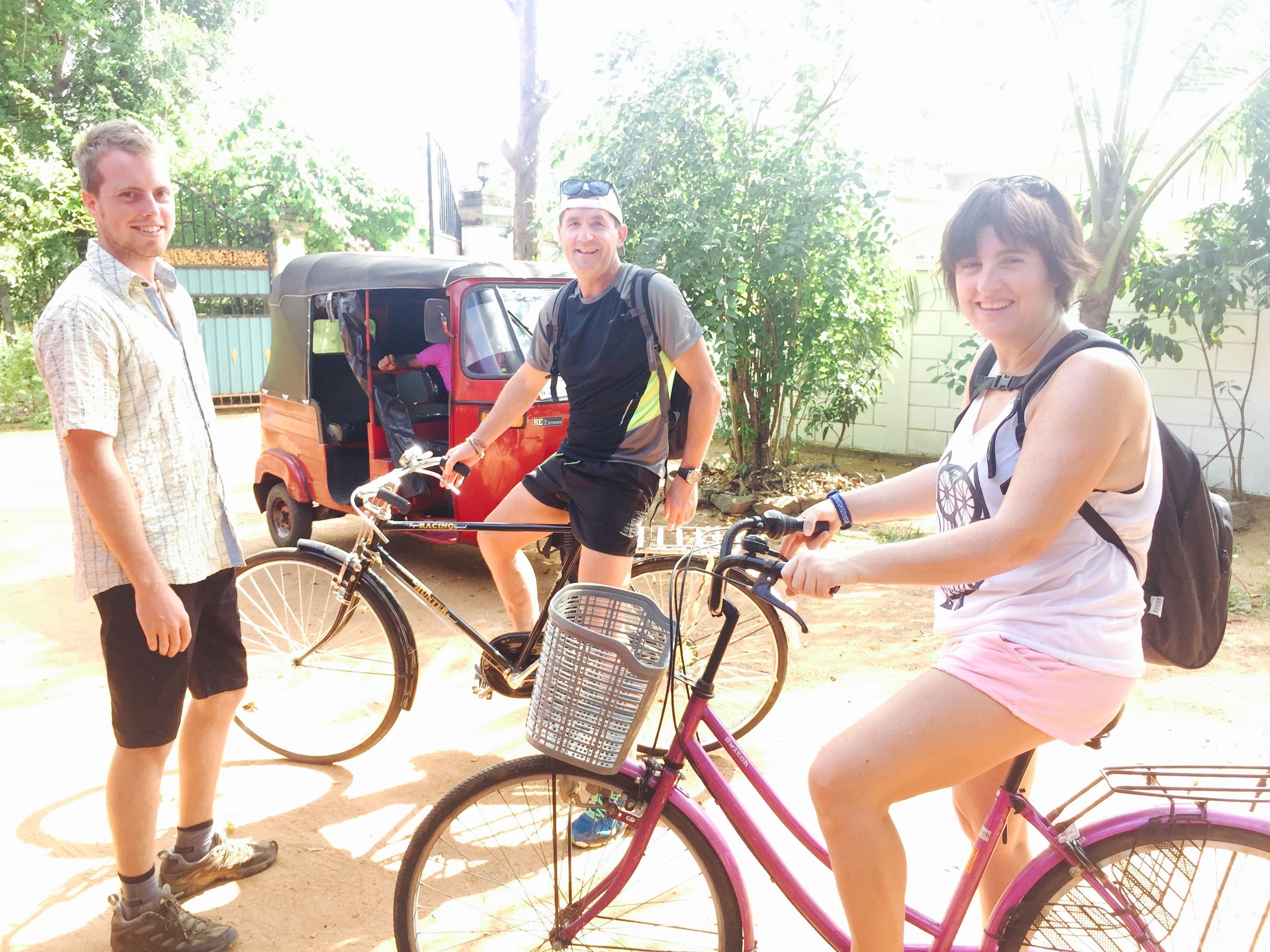 Un grupo de personas de pie alrededor de bicicletas y un tuk-tuk.
