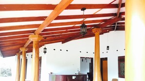 Un espace extérieur abrité, doté de colonnes en bois, d’un comptoir d’accueil et de quelques chaises.