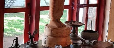 A statue of a seated figure on a pedestal, placed on a wooden table with a window in the background.
