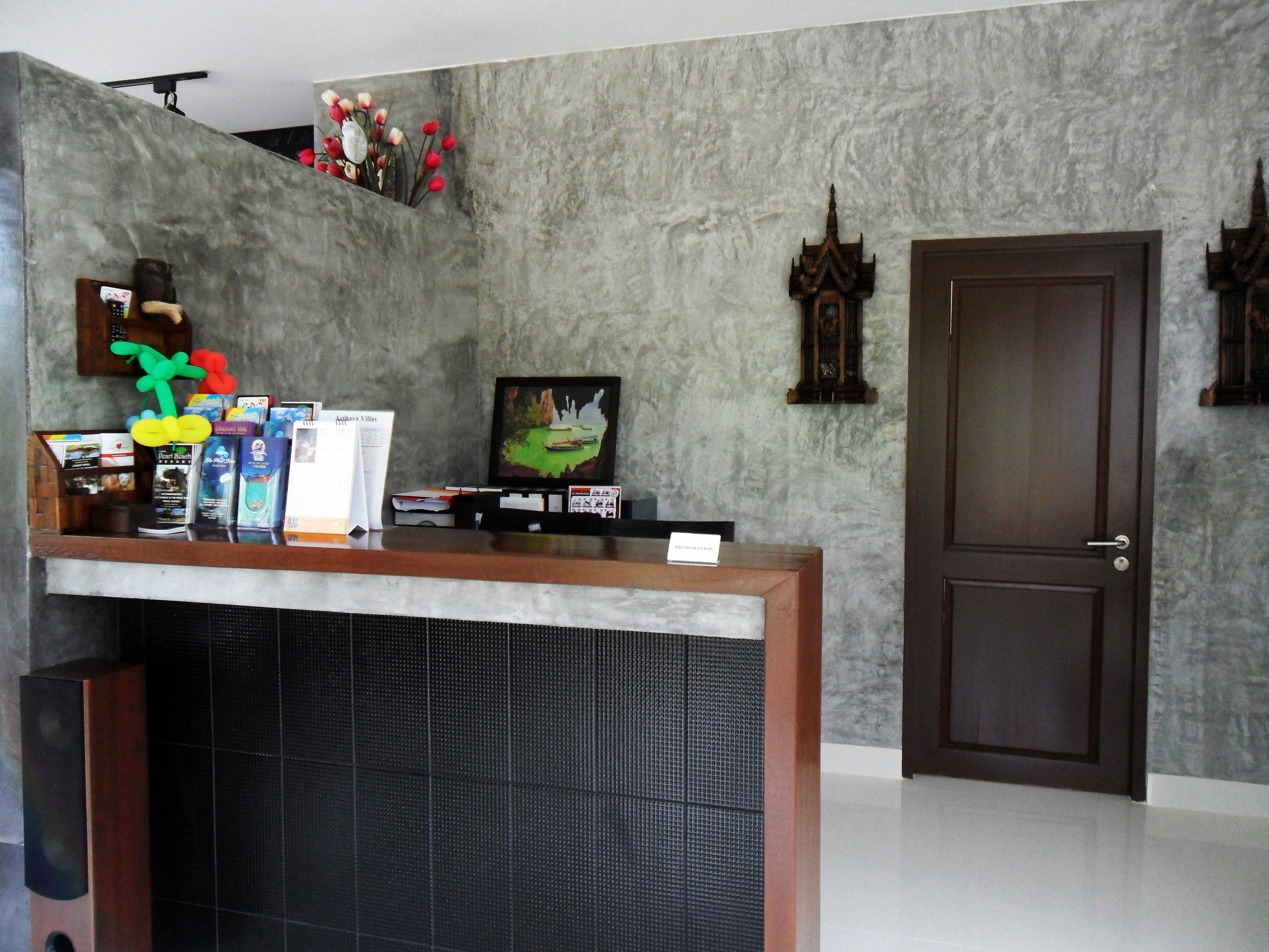 A reception area with a marble wall, a wooden reception desk, a television, and a door.