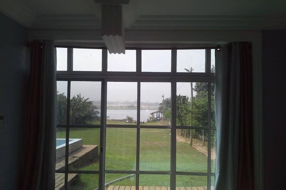 A room with large windows offering a view of a grassy area and a body of water.