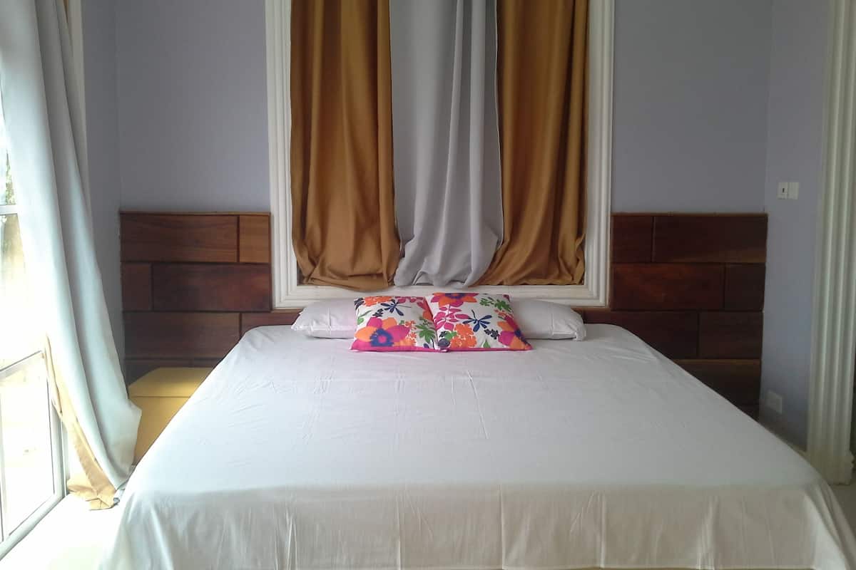 A bedroom with a bed, a headboard, curtains, and a window.