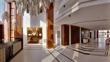 A spacious lobby with a modern design, featuring a reception desk, seating areas, and a large open space with a patterned floor.