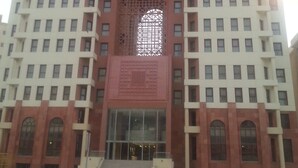 Un hôtel à plusieurs étages, doté d’une entrée centrale en forme d’arc et d’une façade dont les fenêtres sont disposées en réseau.