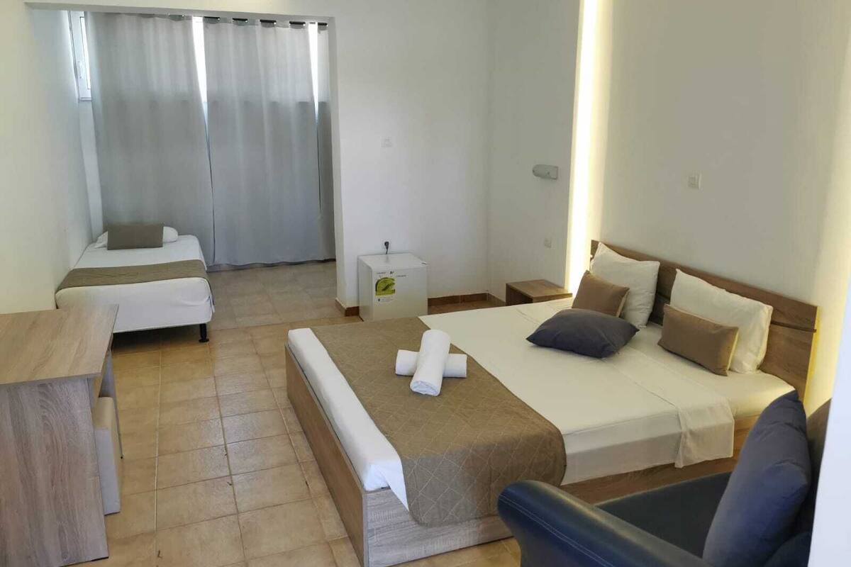 Quarto de hotel com uma cama, um sofá, uma mesinha e uma escrivaninha.