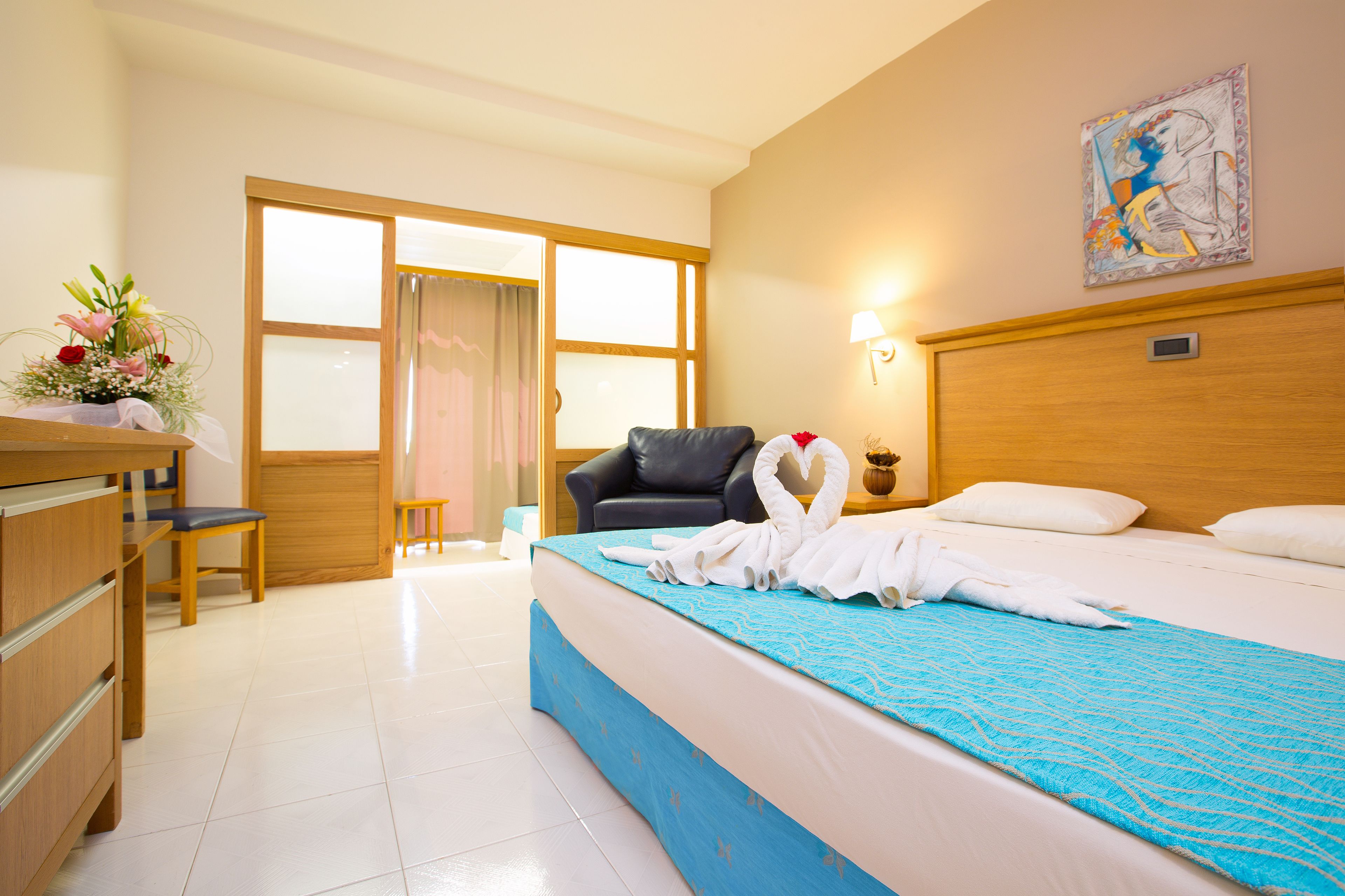 Una camera d'albergo con un letto, una scrivania, una sedia, una testiera in legno e una finestra.