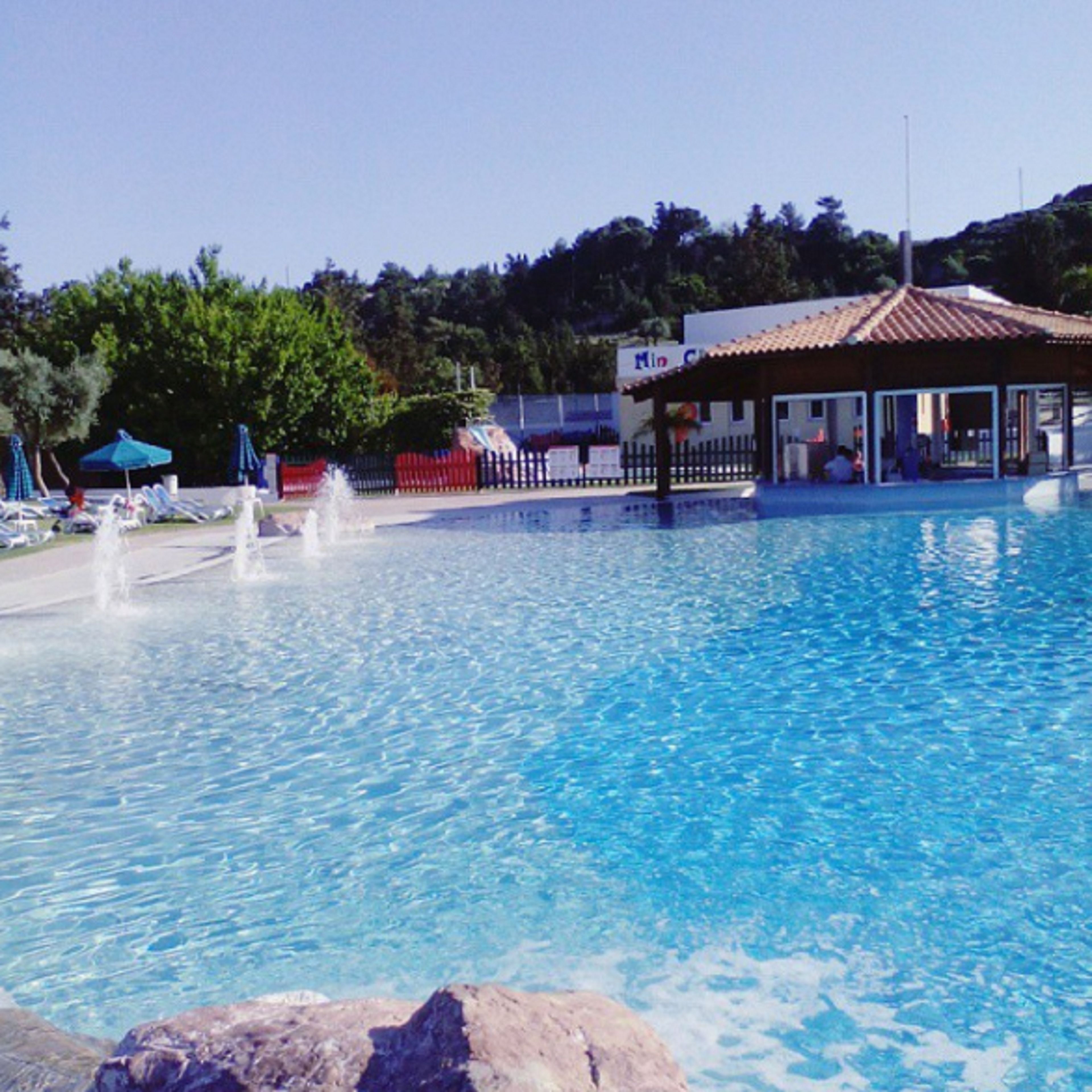 Una piscina con lettini da relax e un padiglione.