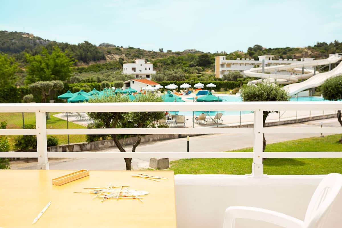 Varanda com vista para uma piscina, espreguiçadeiras e guarda-sóis.