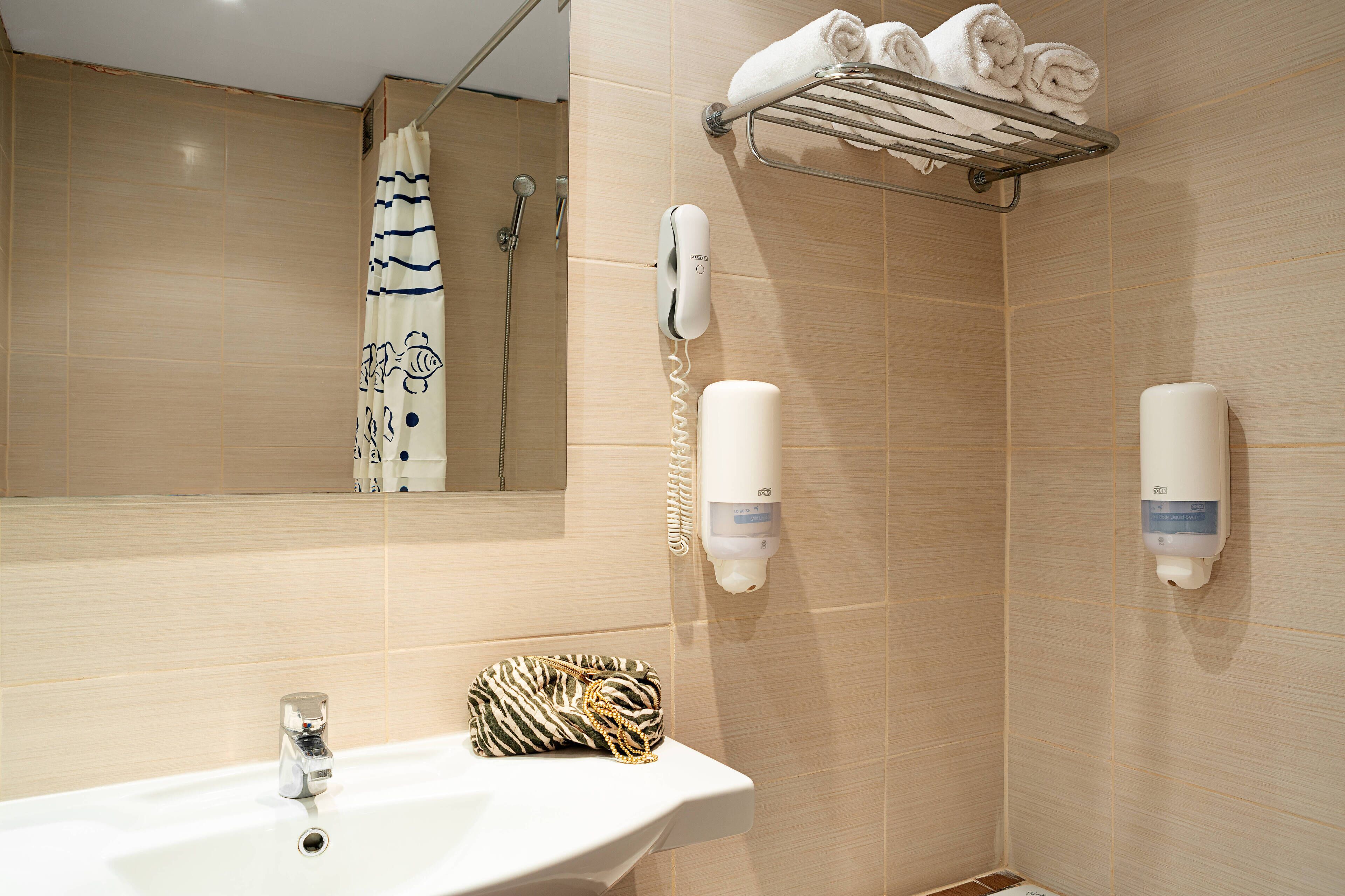 Une salle de bain équipée d’un lavabo, d’un porte-serviettes, d’une douche et d’un sèche-mains.
