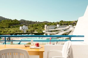 A poolside area with a table, chairs, and a view of a water park with slides.