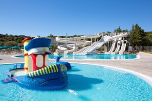 En vattenpark med en stor pool, flera vattenrutschkanor och en färgstark lekplats.