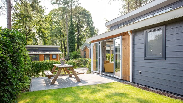 A modern house with a patio, a wooden table, and a sliding glass door. - De Thijmse Berg (Rhenen)