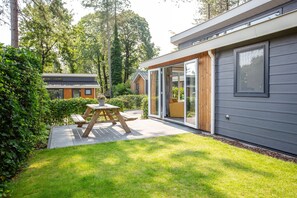Een modern huis met een terras, een houten tafel en een schuifdeur.