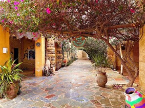 A stone-paved courtyard with a rustic archway, potted plants, and a colorful vase. - Zad Elmosafer Guest House (Yusuf as-Sidiq)