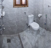 A bathroom with a toilet, shower, and a window.
