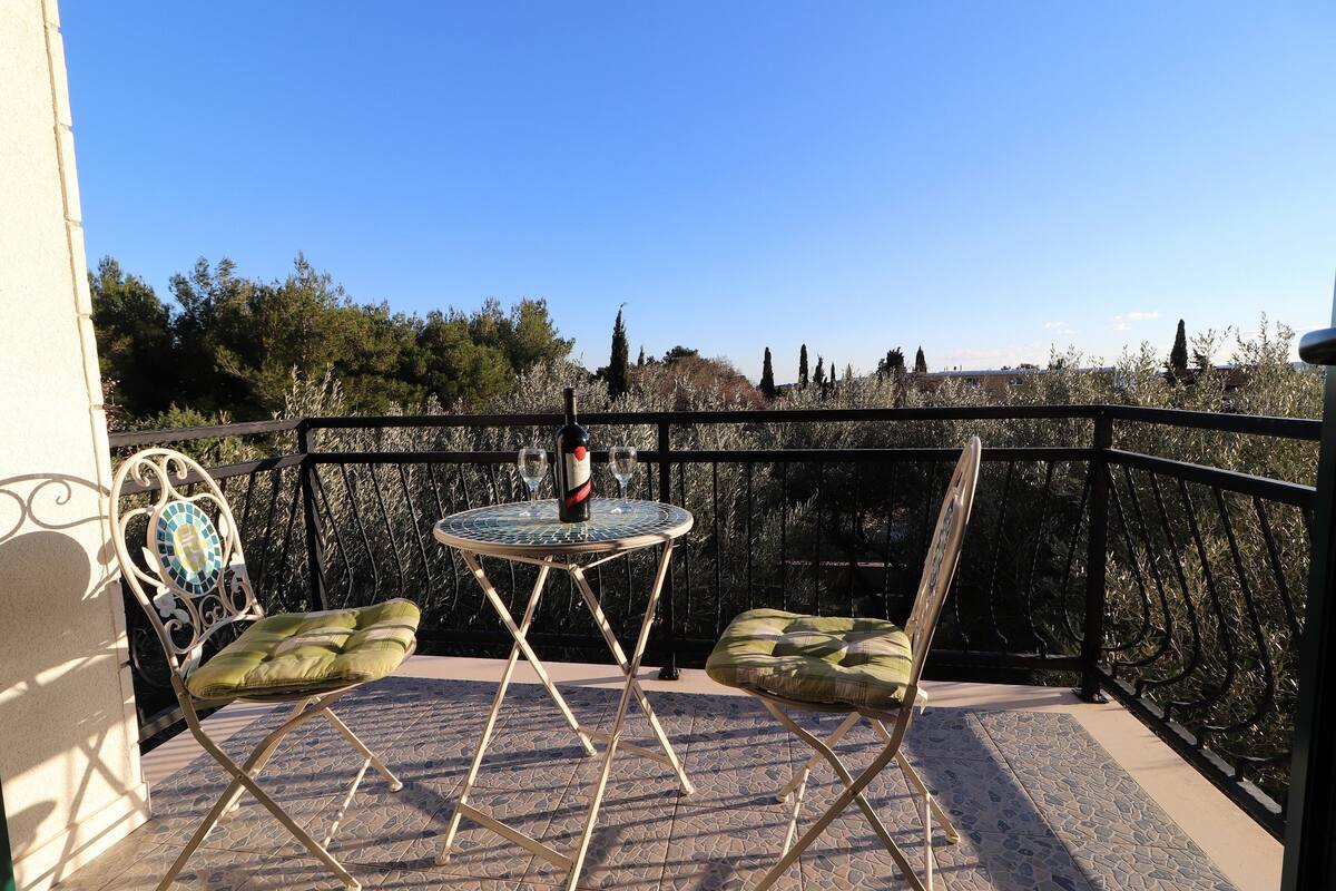 A balcony with two chairs and a table, a bottle, and a glass.
