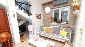 A cozy living room with a white sofa, striped cushions, a globe coffee table, and a small side table with decorative items. - Apartments Trstenica (Orebic)