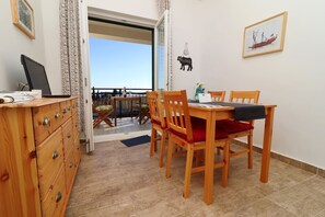 A dining area with wooden chairs and a table, a wooden dresser with drawers, and a view of the outdoors through a door.