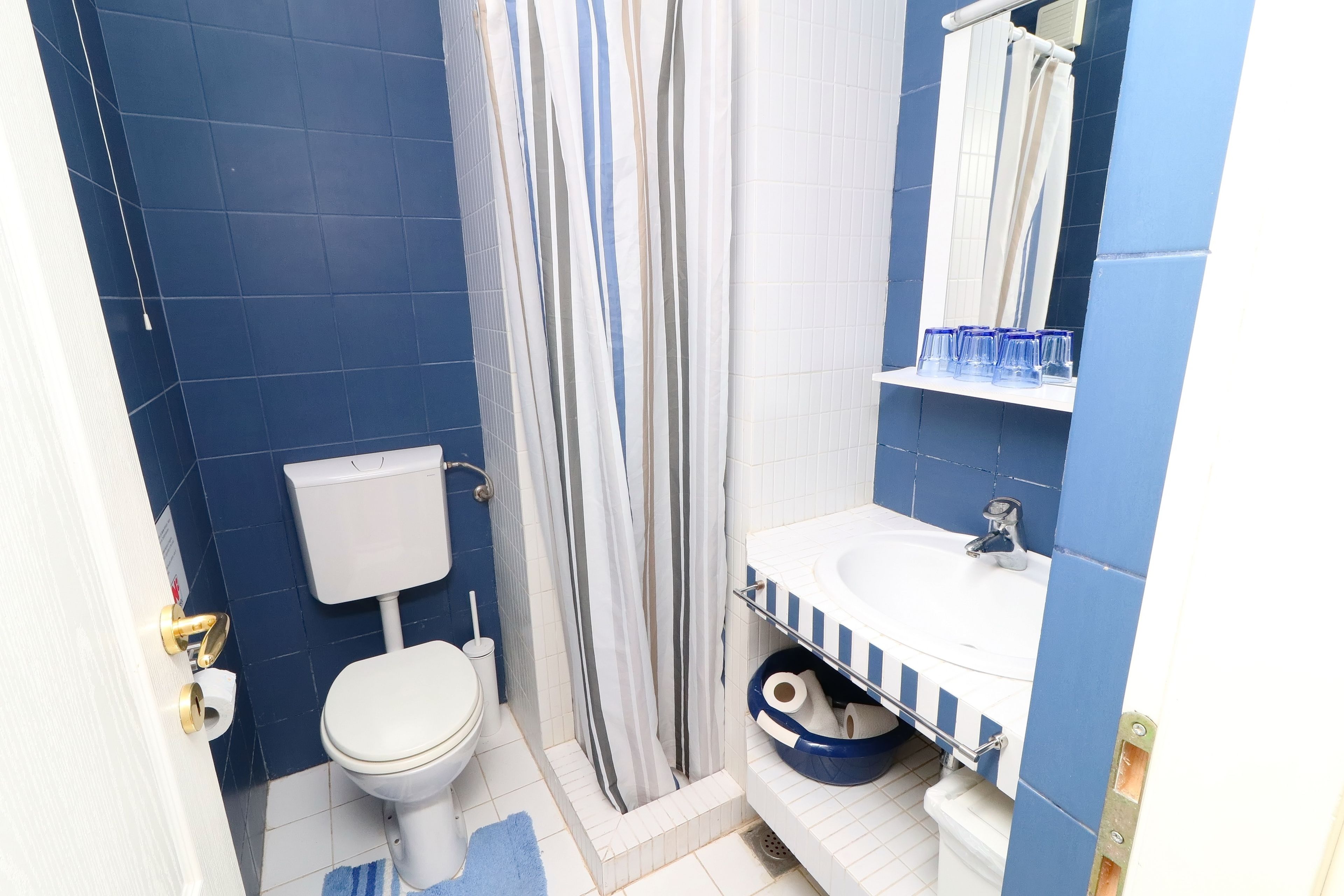 A bathroom with a toilet, shower, and sink.
