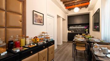 A hotel dining area with a buffet setup, a kitchen in the background, and a modern interior design.