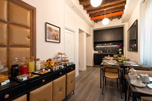 A hotel dining area with a buffet setup, a kitchen in the background, and a modern interior design. - Maison Evelina (Rome)