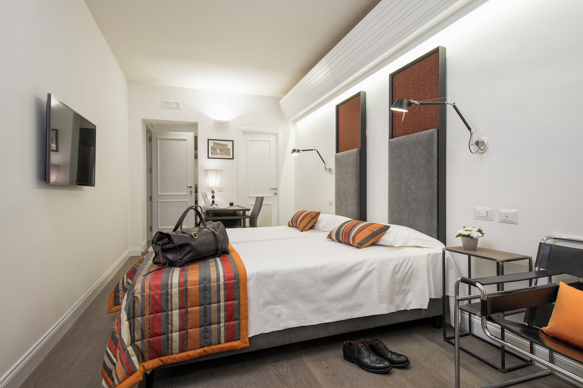 Une chambre d’hôtel avec un lit, un bureau, une chaise et un miroir.