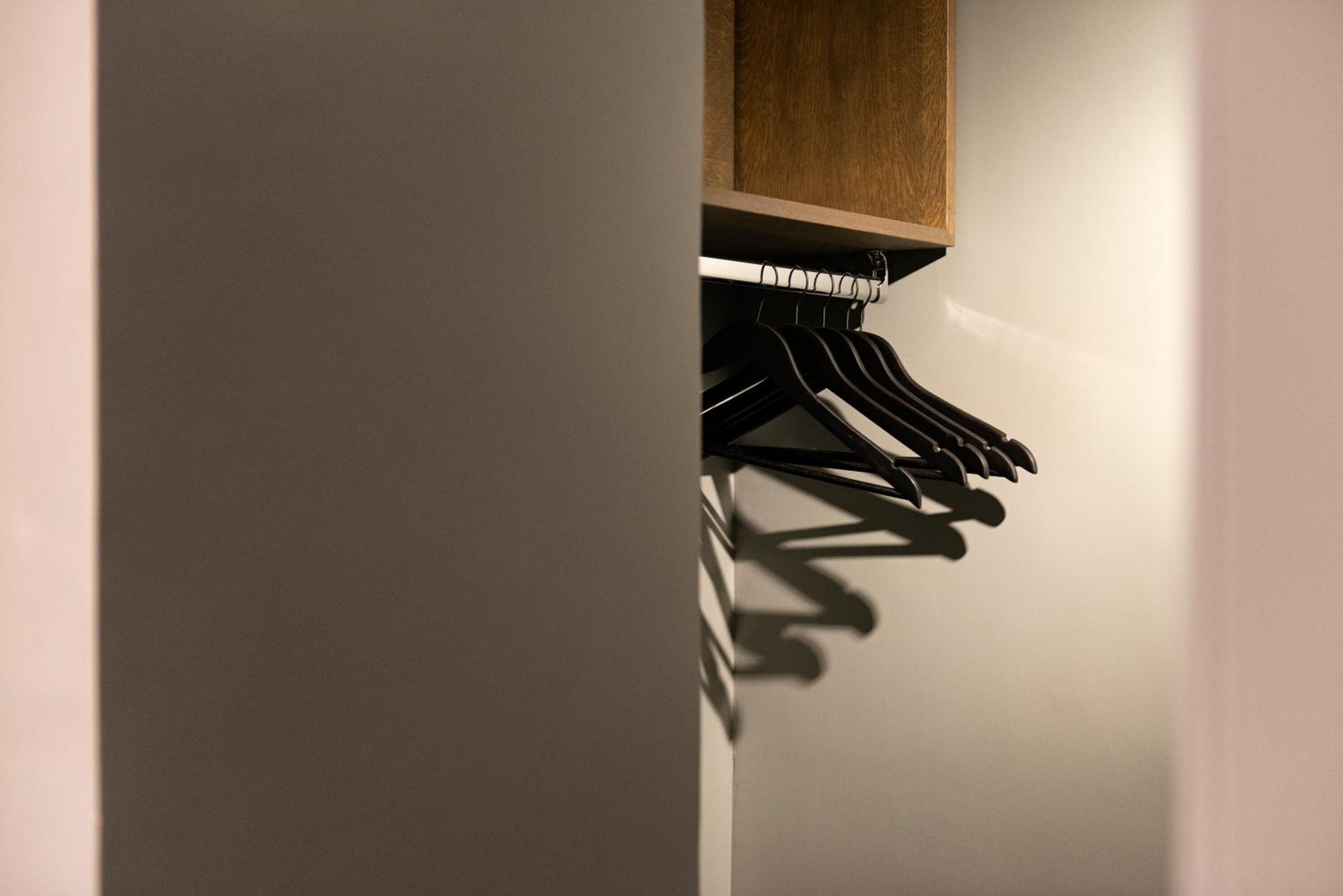Un armario con repisa de madera y barra para colgar ropa negra.