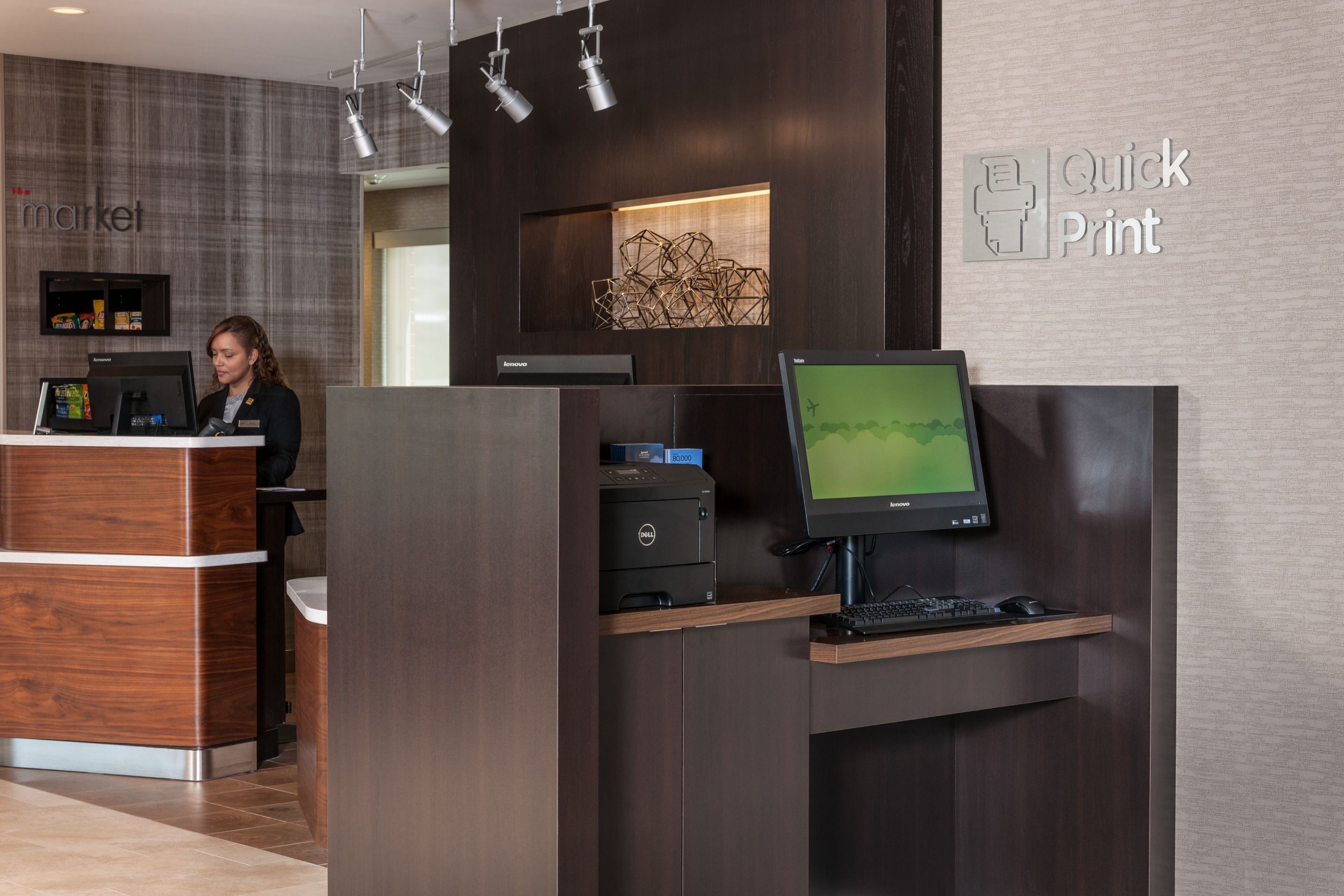 Un mostrador de recepción con un monitor de computadora, una impresora y un letrero que dice 'Quick Print'.