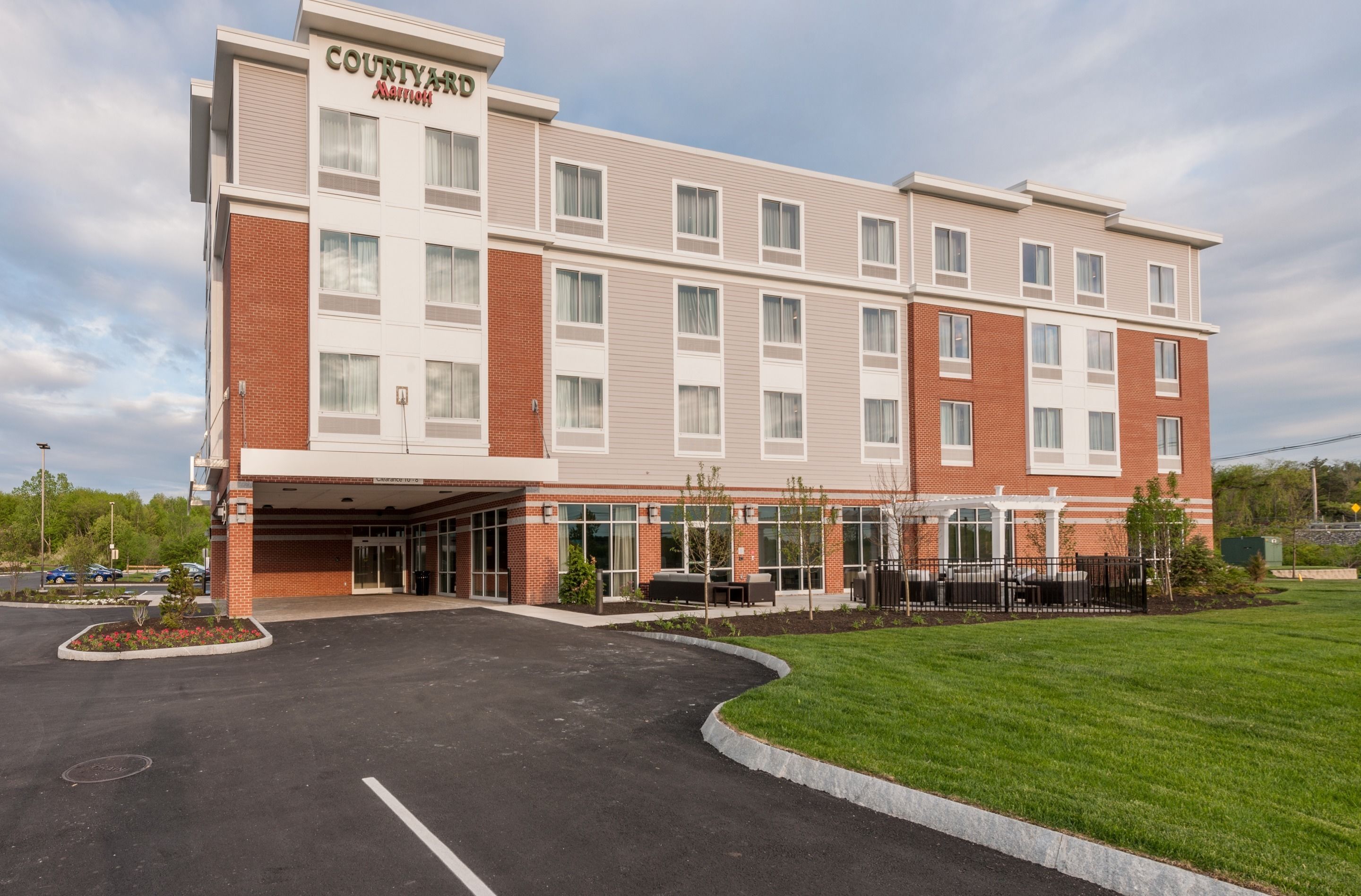 Un hôtel Courtyard Marriott avec une façade en briques, de grandes fenêtres et un parking.